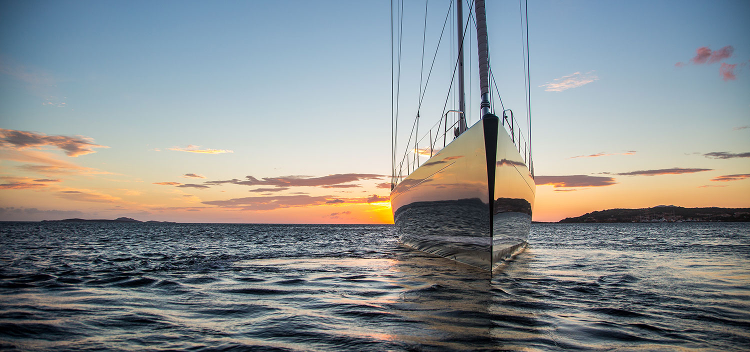 A charter sailing yacht under a setting sun